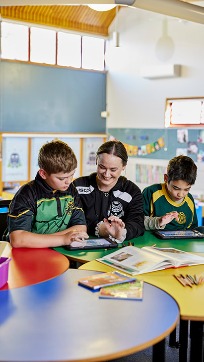 Two primary school students working with a teacher.