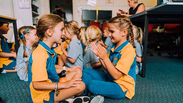 Group of students sitting down on the classroom floor.