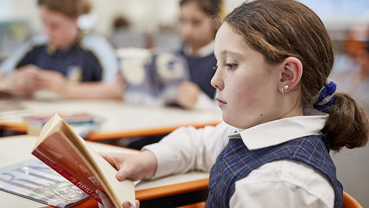 Student reading a book in the classroom.