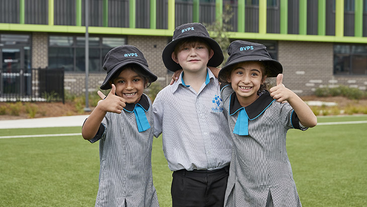 Three students outside with their thumbs up.