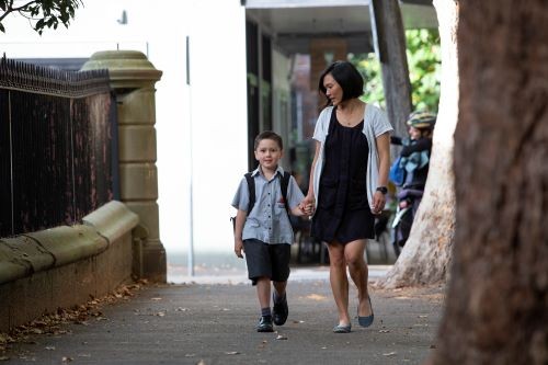 mother and child holding hands walking to school